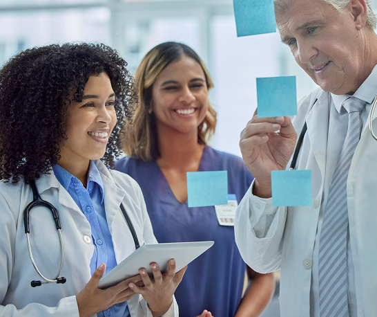 planning-training-doctors-teamwork-glass-board-healthcare-management-internship-workflow-sticky-note-medical-students-people-woman-with-manager-writing-ideas-clinic-goals 1